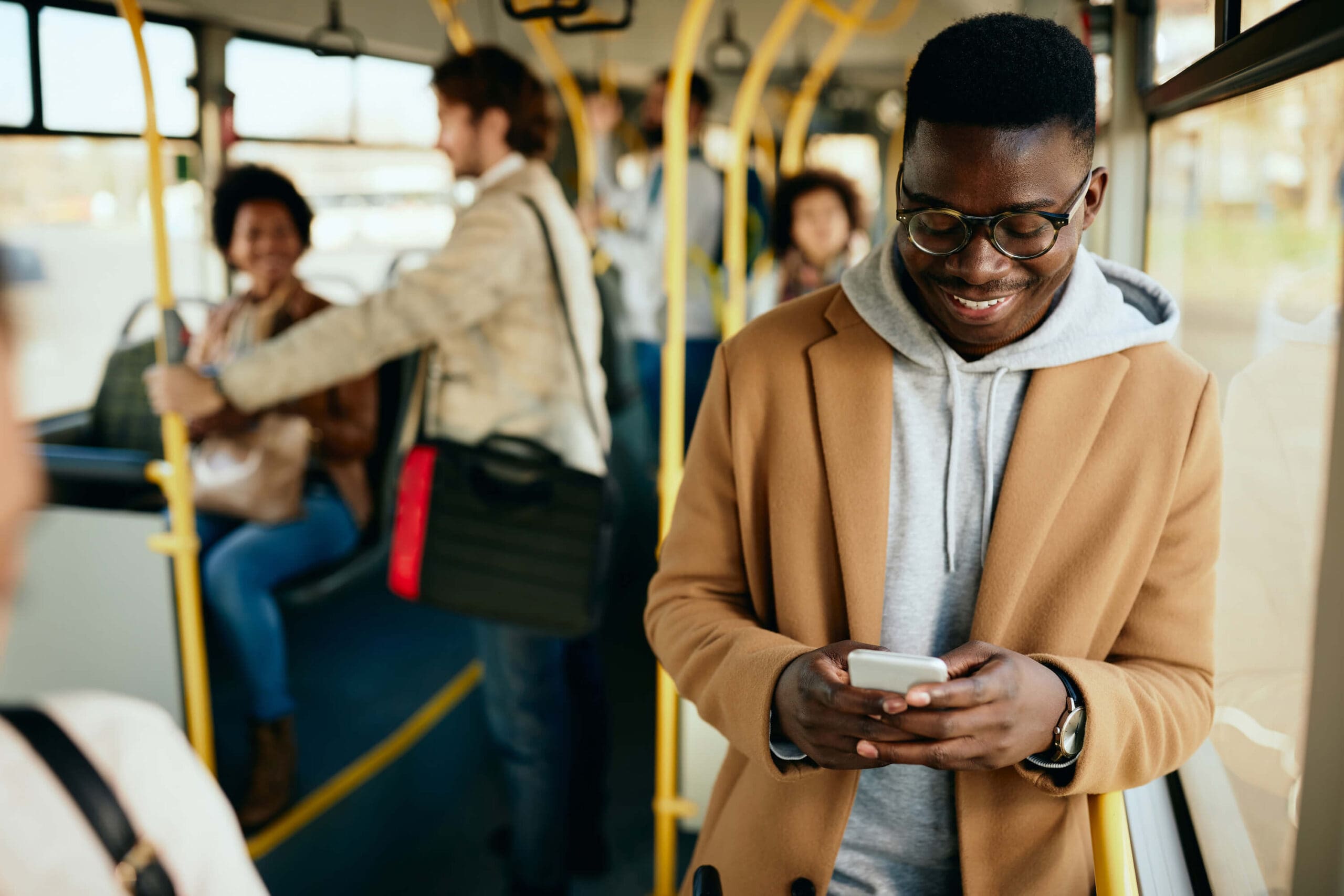 happy-african-american-man-texting-mobile-phone-while-commuting-by-bus